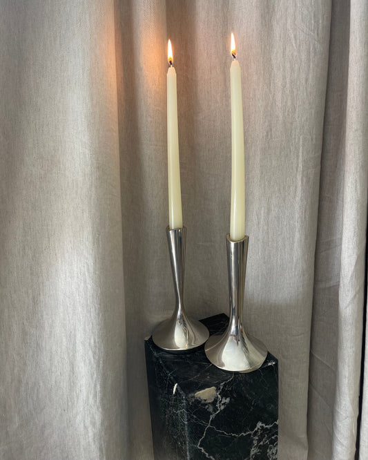 Two silver candlesticks on a marble surface